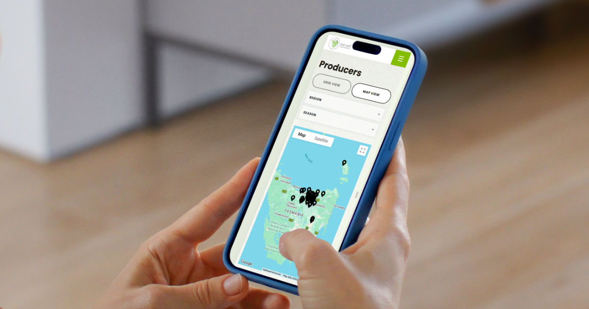 A mobile phone is being held showing a map of Tasmania